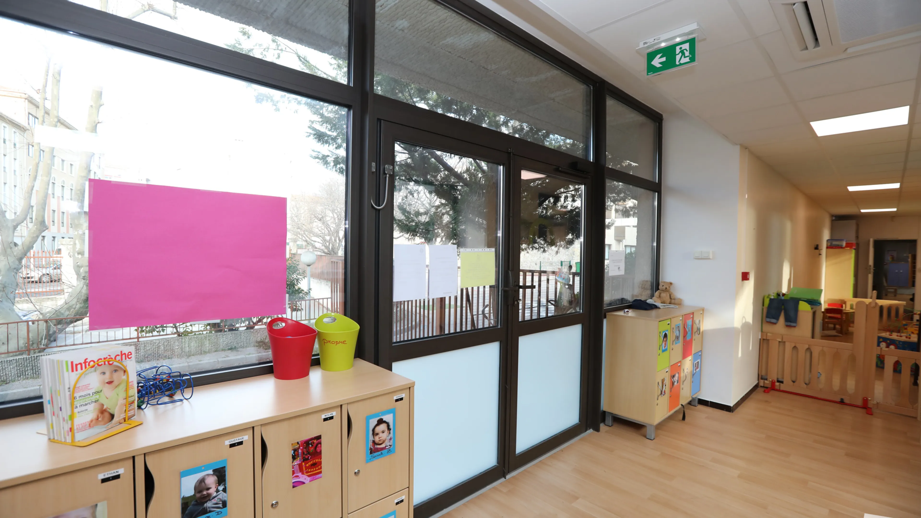 Photographie de l'intérieur d'une salle de crèche, sur laquelle on aperçoit la porte d'entrée et des rangements