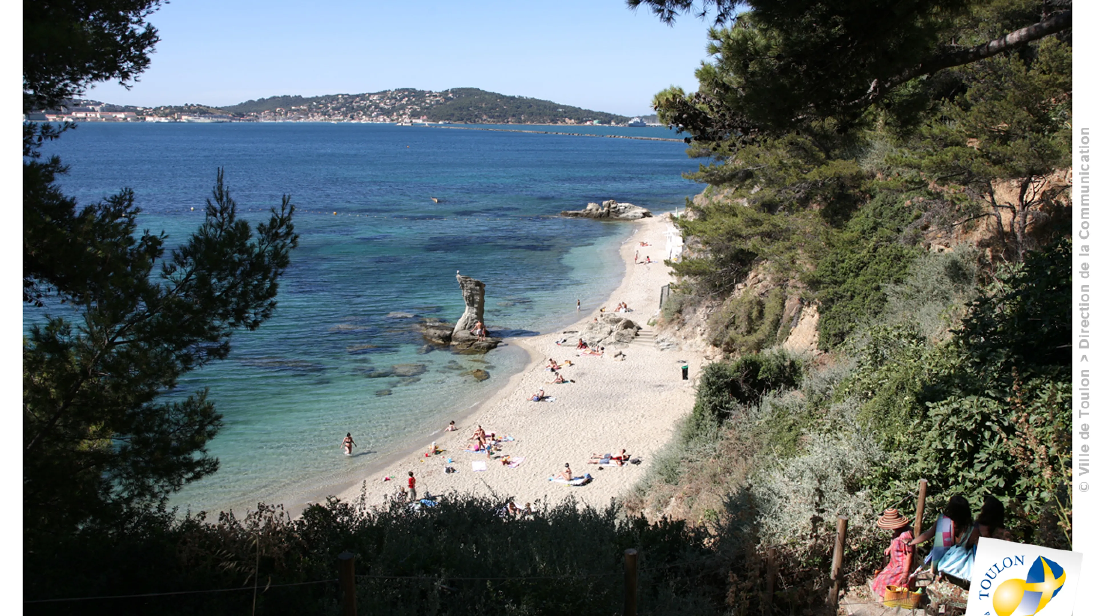 Photographie de la Plage de la Mitre sur laquelle on peut apercevoir au loin plusieurs personnes allongés sur le sable, et quelques-uns dans l'eau