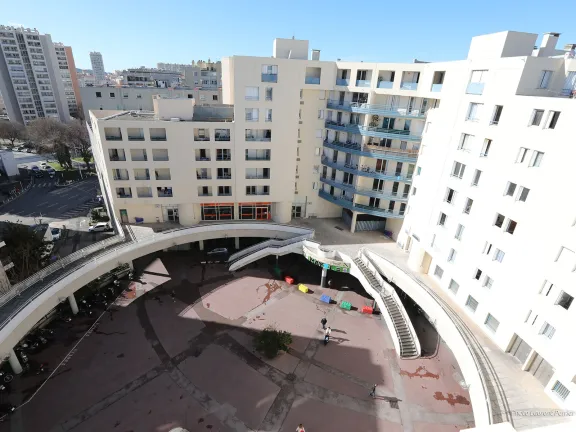Place donnant sur l'entré du centre commercial Mayol, ainsi que des escaliers donnant sur une passerelle qui entoure la place