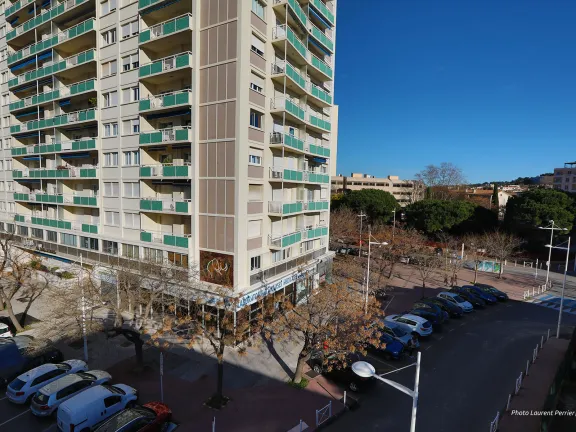 Place arborée avec places de stationnement au pied d'un immeuble