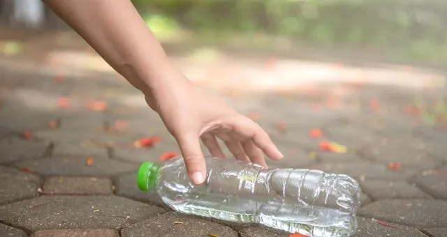 Photo d'une personne qui ramasse une bouteille plastique